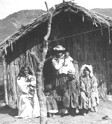 Maori family pose outside their whare